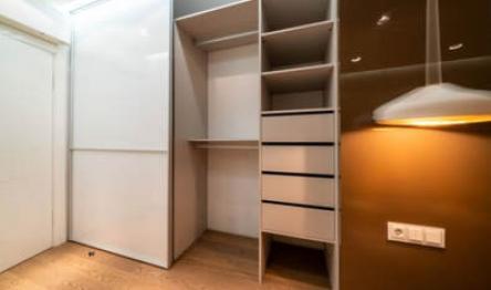 Minimalist walk-in closet with white shelves and ambient lighting.