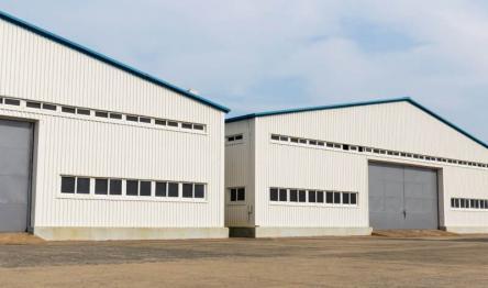 Industrial white warehouses with large doors and horizontal windows.