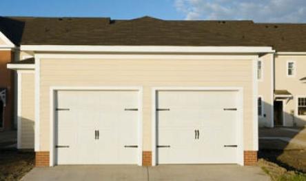 Suburban double garage with white doors on a cream-colored facade