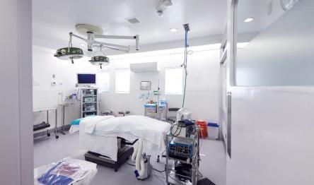 Fully equipped operating room with surgical table and overhead lights.