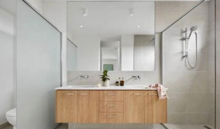 Sleek bathroom with wooden vanity, large mirror, and glass shower.