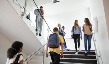 Students chatting and walking up the white staircase in a school.