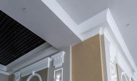 Elegant interior ceiling corner with decorative moldings and a vent grille.